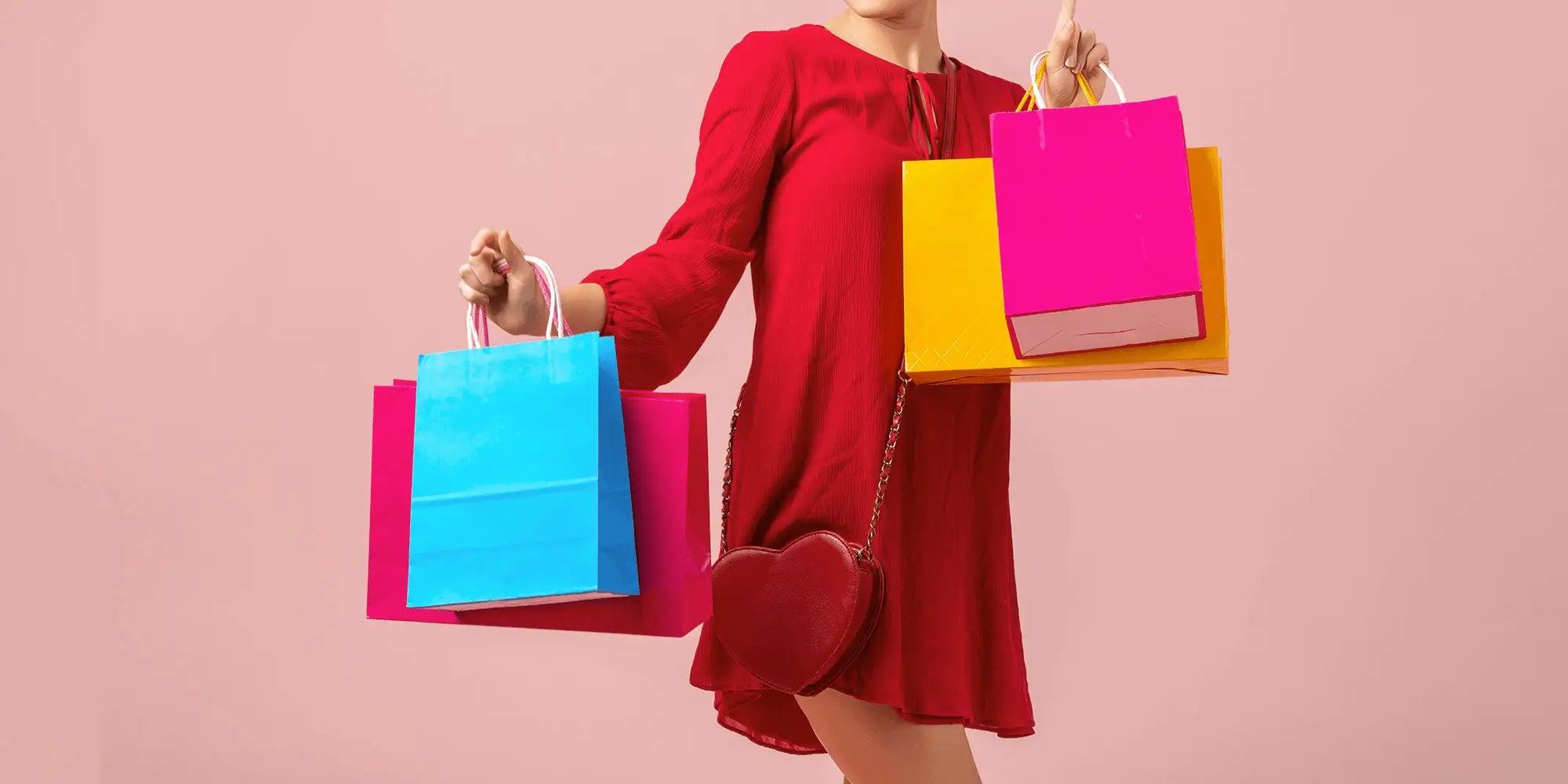 Banner für die Kategorie „SALE für Damen“ im Boxxers Online Shop. Eine Frau trägt ein rotes Kleid und hält mehrere farbige Einkaufstüten in Blau, Pink und Gelb vor einem rosafarbenen Hintergrund.