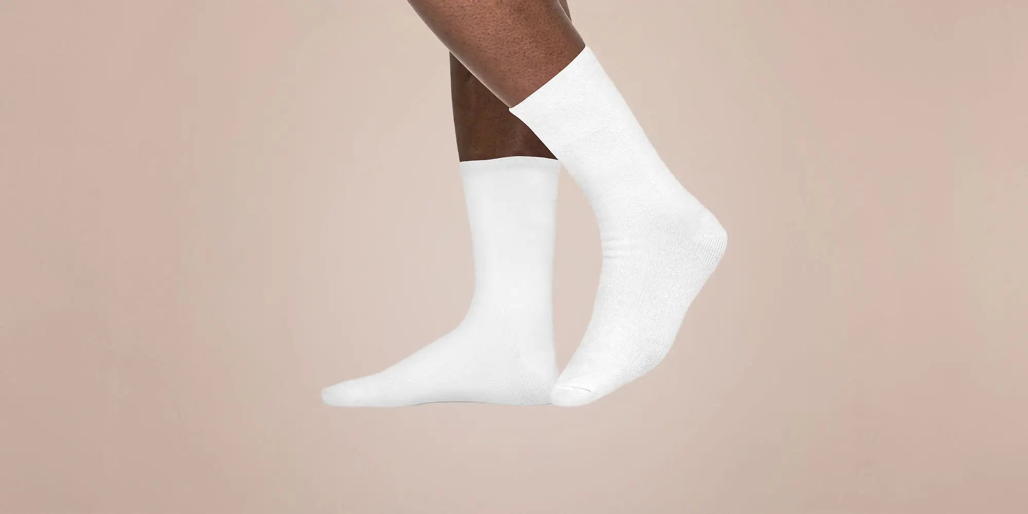 Banner für die Kategorie „Herren Socken & Strümpfe“ im Boxxers Online Shop. Ein Mann trägt weiße, knöchelhohe Socken und streckt die Beine leicht angewinkelt vor einem beigefarbenen Hintergrund aus.
