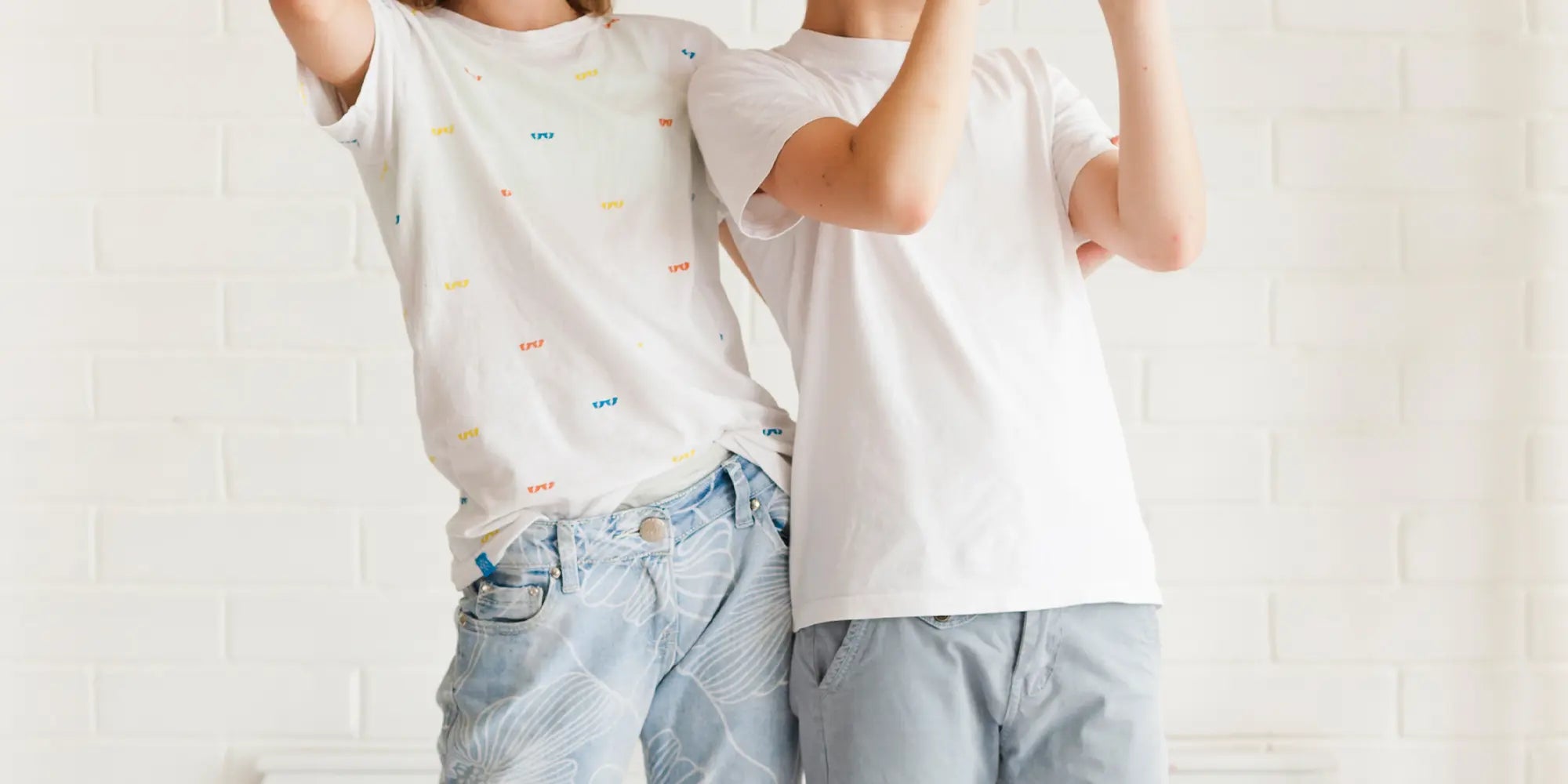 Der Banner zeigt kindgerechte Mode für die Kategorie „Kinder“. Zwei Kinder tragen helle T-Shirts und leichte Sommerhosen und stehen fröhlich nebeneinander vor einer weißen Wand.